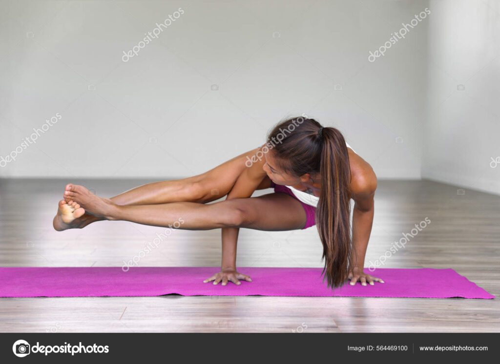 Yoga woman strength training on exercise mat doing yoga poses exercises at gym. Difficult pose, astavakrasana, asymmetrical arm balance eight Angle Pose